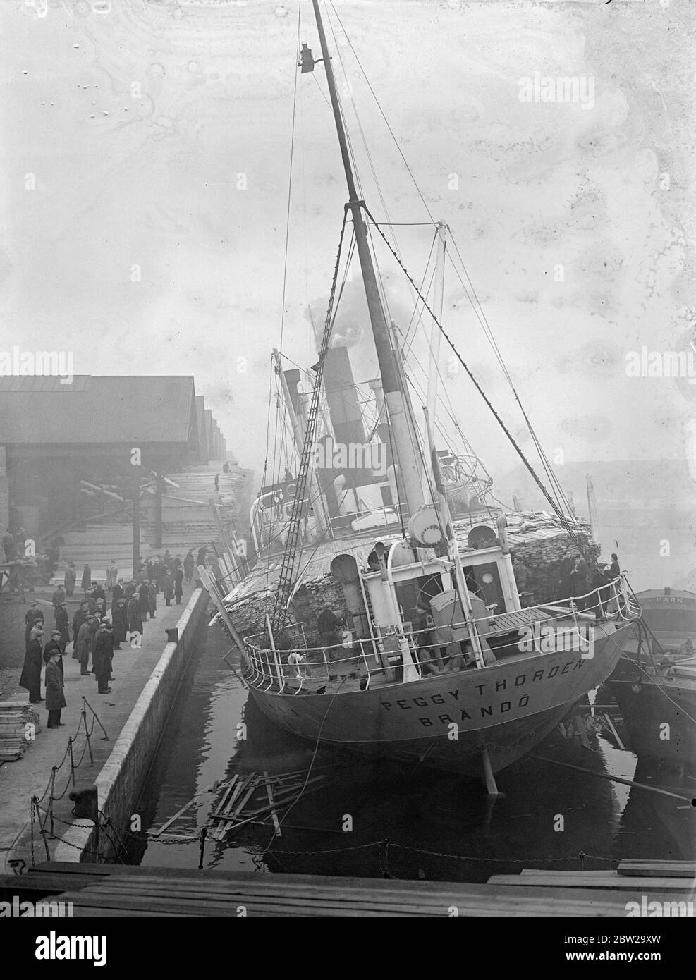 Dampfer mit Liste der 20Â in Surrey kommerziellen Docks, Frachtschiffe in schwerer See. Die finnische Dampfer 'Pegy Thorden' befindet sich im Hafen von QuÃ©bec, Surrey Commercial Docks, nachdem ihre Holzladung auf der Reise von Walkom auf der schweren See verschoben wurde und eine Liste von Grad verursachte. Einmal waren die Decks im QuÃ©bec Dock überflutet, und die Stevedores warteten darauf, dass das Gleichgewicht der Schiffe wiederhergestellt wurde, bevor sie sie entladen. Dezember 1937 Stockfoto