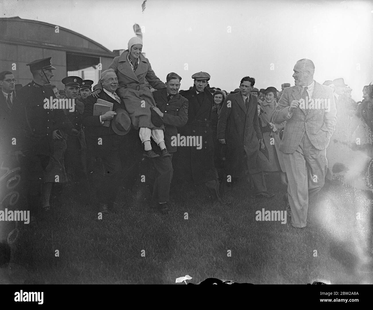 Jean Batten schlägt Australien nach England Rekord um 14 1/2 Stunden. Nachdem sie in ihrer letzten zermürbenden Runde gegen Erschöpfung und Stürme gekämpft hatte, wurde Jean Batten, das neuseeländische Luftmädchen, von jubelnden Menschenmengen begrüßt, als sie in Croydon landete, nachdem sie Jim Broadbents Rekord von Australien nach England um 14 1/2 Stunden gebrochen hatte. Sie war in Lympne gelandet, hatte in fünf Tagen 18 Stunden den ersten Alleinflug absolviert und kam nach Croydon. Foto zeigt, dass Jean Batten auf den Schultern der Menge getragen wird, die sie zurück nach England begrüßte. 24. Oktober 1937 Stockfoto