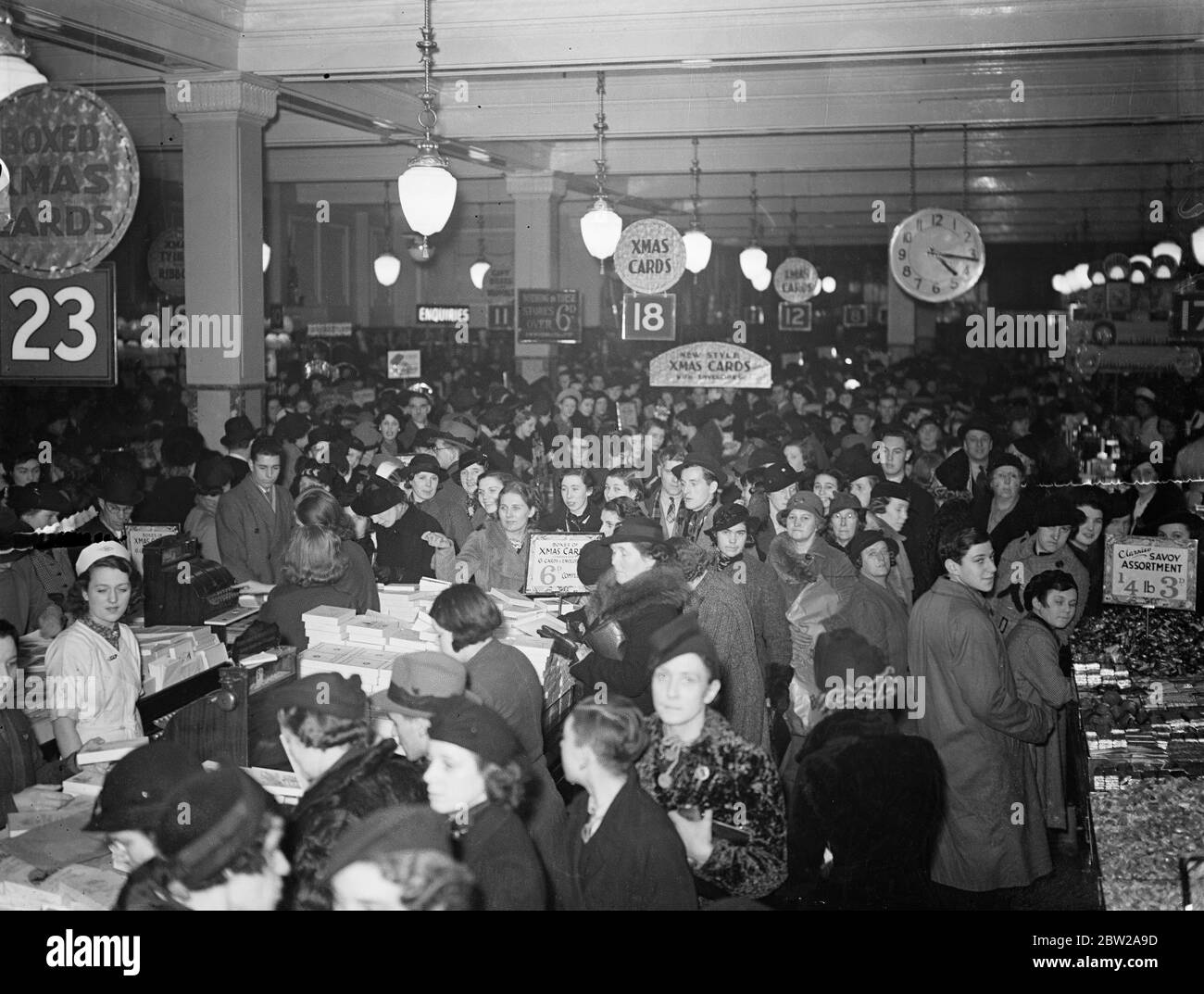 Weihnachtseinkäufe drängten sich durch die West End-Geschäfte. Nutzen Sie die verlängerten Öffnungszeiten, die große Menschenmassen drängen die großen West End-Geschäfte auf der Suche nach Weihnachtsgeschenken. Fotoausstellungen, ein überfüllter, dekorierter Laden in der Oxford Street, der von Last-Minute-Käufern überfüllt ist. 20 Dezember 1937 Stockfoto