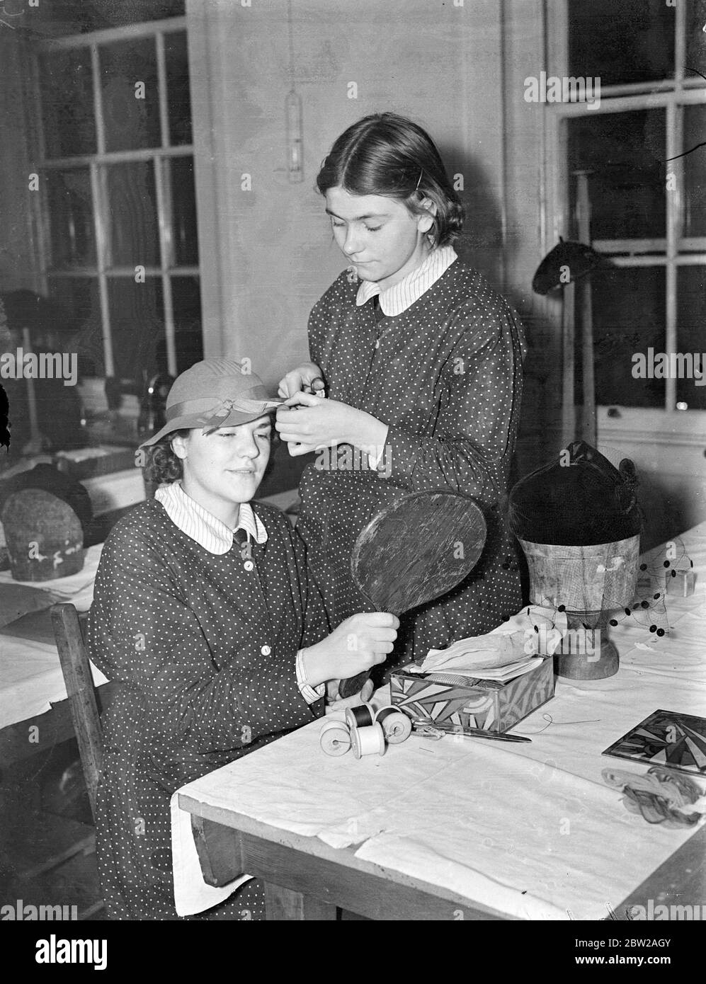 Schulmädchen Dressmaker bereiten für ihre eigene Ausstellung. Junge Schneiderinnen, Putzfrauen und Schneiderinnen arbeiten hart an der Bloomsbury (London County Council) Trade School am Queens Square und bereiten die Modelle für ihre eigene Ausstellung vor, die am ersten des nächsten Monats stattfinden wird. Foto zeigt, ein junger Müller Abschluss einen Hut für die Ausstellung in der Trade School, Queen Square, Bloomsbury.. 27. November 1937 Stockfoto