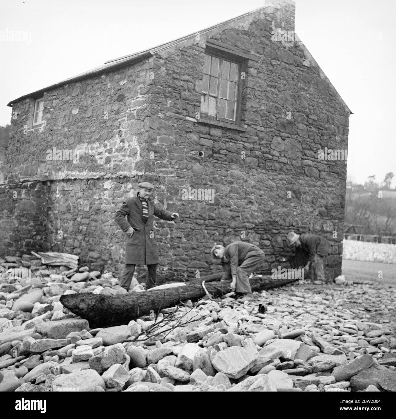 Einige der Dorfbewohner im bedrohten Amreth an der Küste von Pembrokeshire in Wales haben den Kampf gegen den Atlantik aufgegeben und sind gezwungen, ihre Häuser am Meer zu verlassen. Von den hohen Fluten des Frühlings zerschlagen, wurden mehrere Hütten mit Blick auf den Atlantik zerstört und ihre Besitzer gezwungen, ihre Häuser zu verlassen. Die Dorfbewohner haben die Meeresmauer verstärkt, um zu verhindern, dass die Wellen durchbrechen und das Dorf auslöschen. Foto zeigt zerstörte Hütten, mit Massen von Kieselsteinen gegen die Reste der Wände gehäuft. Februar 1939 Stockfoto