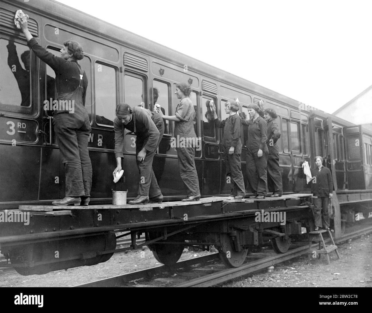 Frauen, die Schäuber und Reinigungskräfte auf der London und South Western Railway in Wimbledon reinigen einen Eisenbahnwaggon. 1917 Stockfoto