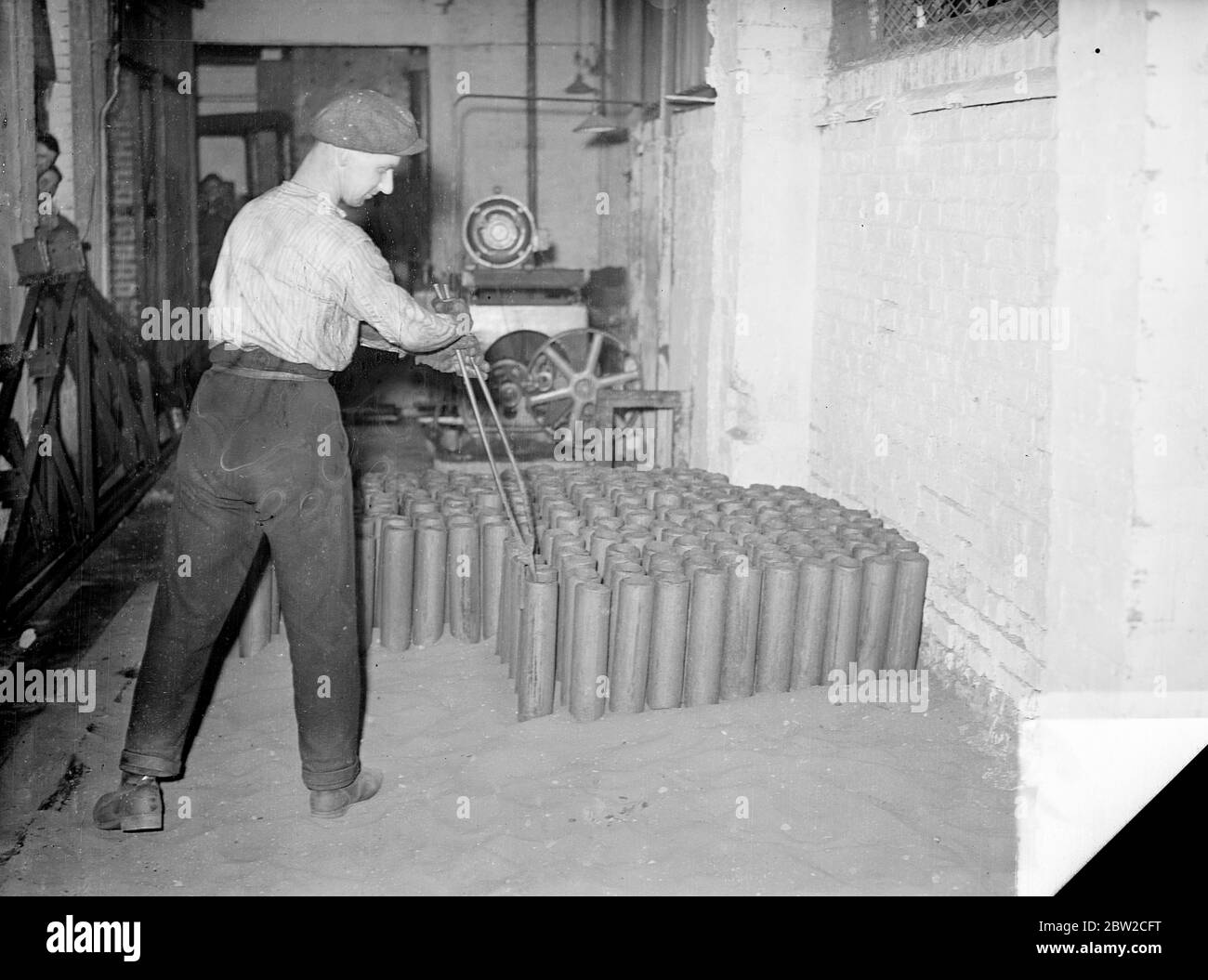 Arbeiter, die rote heiße geschmiedete Muscheln in Sand in einer britischen Muschelfabrik - einer der größten Europas - irgendwo in England platzieren, wo Männer Tag und Nacht arbeiten, um Aufträge für das Versorgungsministerium zu erfüllen. 18. November 1939 Stockfoto