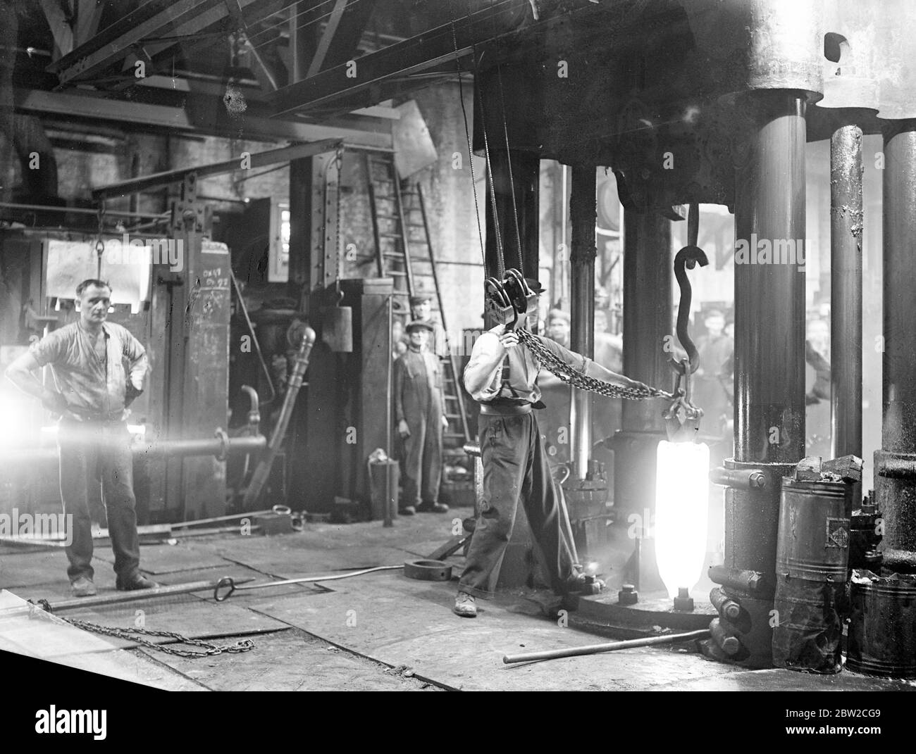 Männer, die im Glanz eines Strahlofens in einer britischen Muschelfabrik - einer der größten Europas - irgendwo in England arbeiten, wo Männer Tag und Nacht arbeiten, um Aufträge für das Versorgungsministerium zu erfüllen. 18. November 1939 Stockfoto