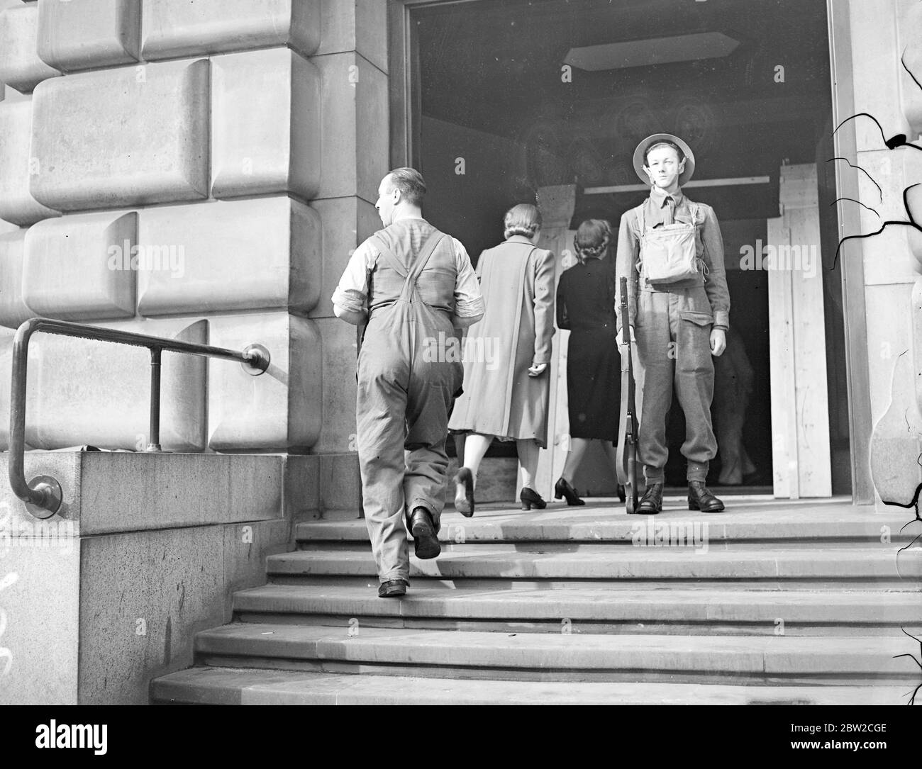 Ein Soldat in voller Kriegsausrüstung auf Wache im Büro an der Themse, als Mädchenangestellte wie gewohnt zur Arbeit kamen. September 1939 Stockfoto