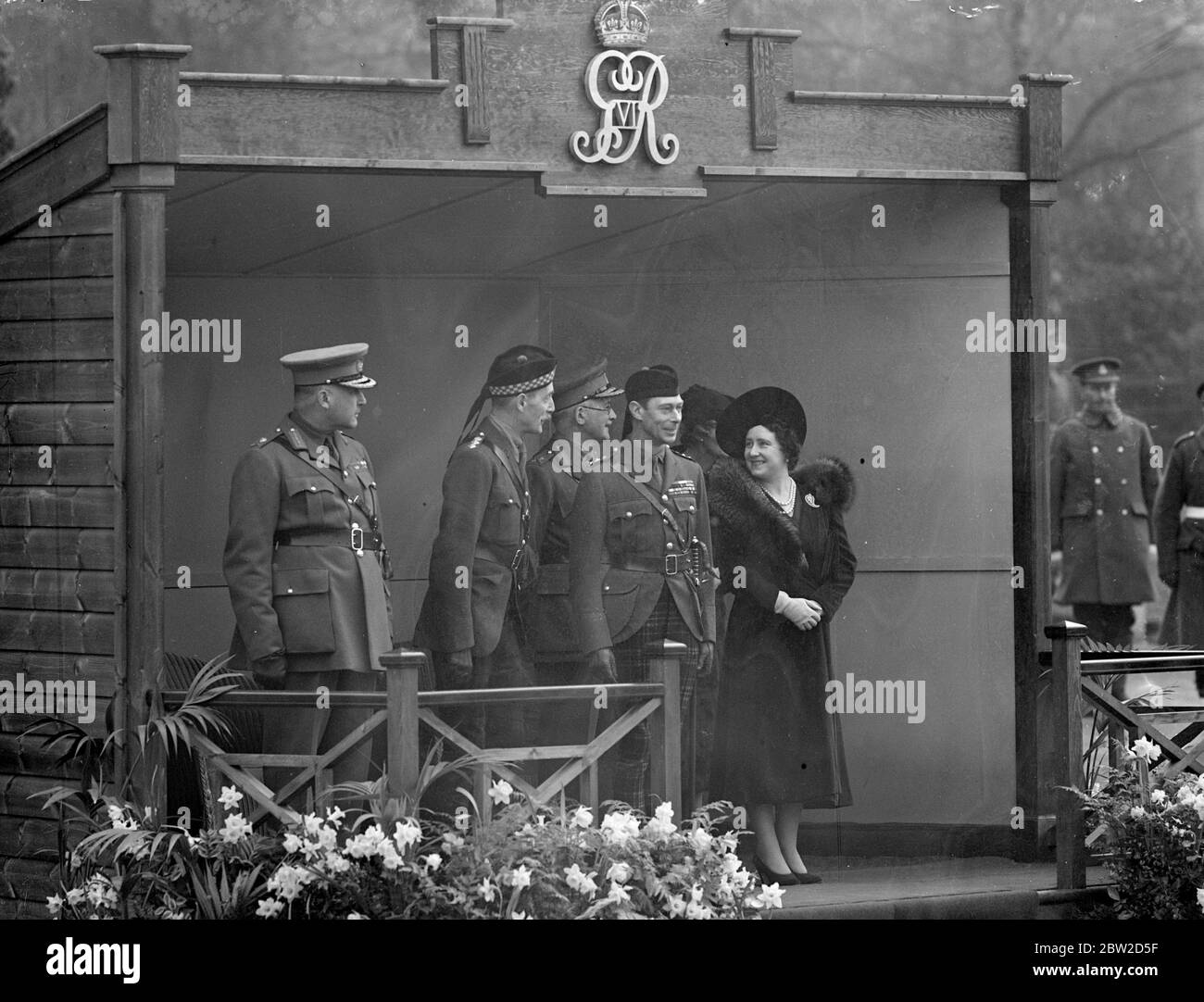 Der gerade aus Sandringham zurückgekehrt König George VI. Und Königin Elizabeth nahmen an der Einweihung des neuen Westflügels der St. Andrews Garrison Church of Scotland in Aldershot Camp, Hampshire, Teil und inspizierten anschließend die Schotten-Regimenter. Foto zeigt: Der König und die Königin auf der Salutsbasis mit Sir Ian Hamilton während des vormarsches. Februar 1939 Stockfoto