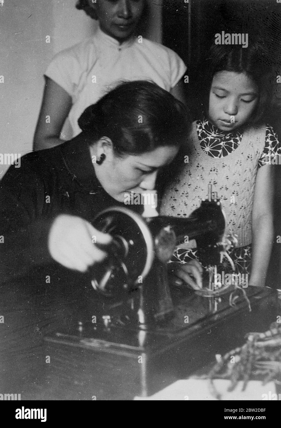 Madame Chiang Kai-shek, Frau des chinesischen Generalissimo und First Lady of China, hat sich Zeit genommen von Staatsangelegenheiten, in denen sie eine der vertrauenswürdigsten Beraterinnen ihres Mannes ist, um unter der Schirmherrschaft der New Life Women's Working Groups Kleidung für Soldaten und Flüchtlinge zu nähen, Die ihren Sitz im Yokohama Special Bank Gebäude in Hankow haben, dem provisorischen chinesischen Hauptquartier. Foto zeigt: Madame Chiang betreibt eine Nähmaschine im Hauptquartier. Ein kleines Mädchen ist ein interessierter Zuschauer. 21. Oktober 1938 Stockfoto