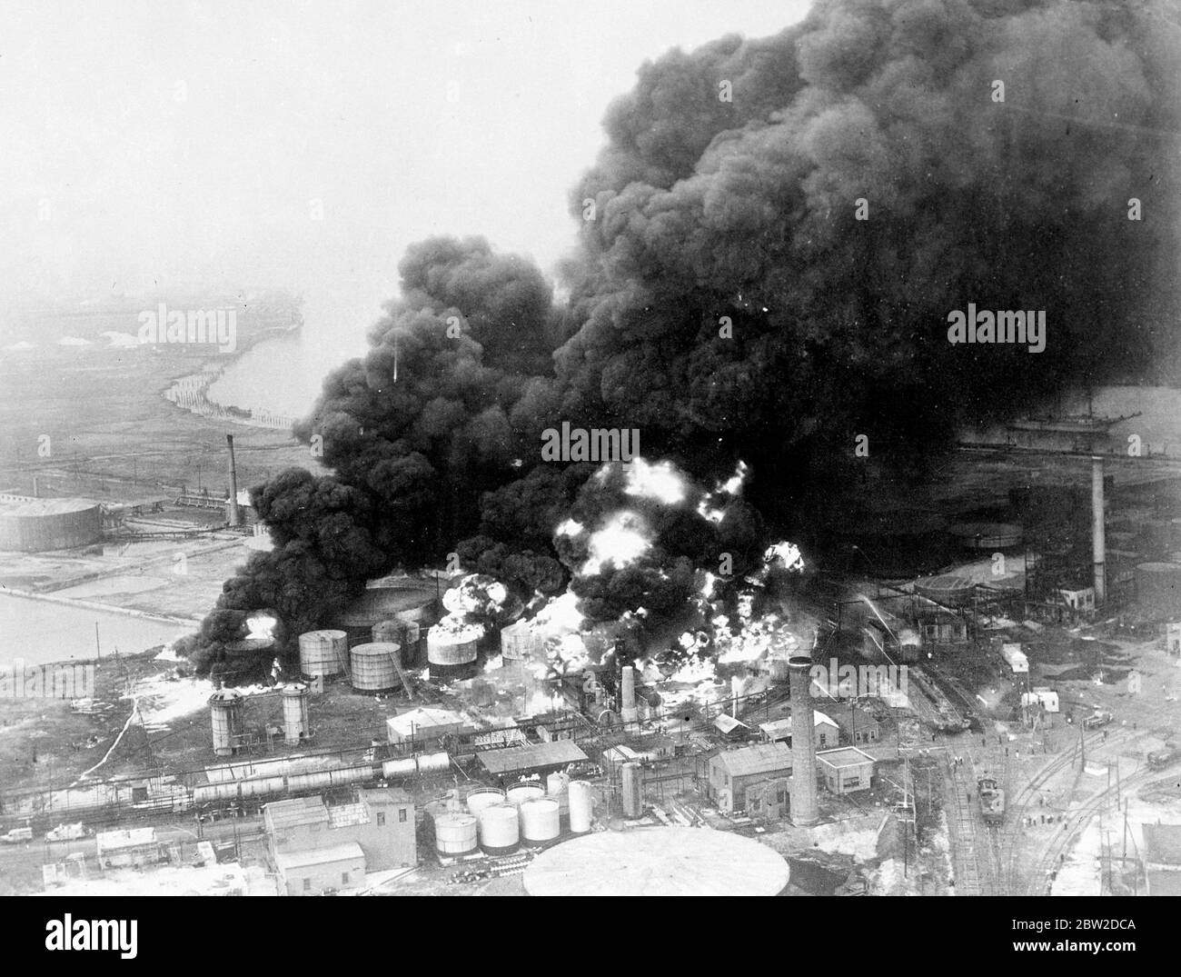 Die schwarzen Wolken aus öligen Rauch und lauernden Flammen, die aus der brennenden Warner Quinlan Oil Refinery-Anlage in Linden, New Jersey, aufsteigen, nachdem eine Explosion die Tanks zerstört und Trümmer von brennenden Öl über ein weites Gebiet verbreitet hatte. Die Züge mussten am 19. Oktober 1938 umgelenkt werden Stockfoto