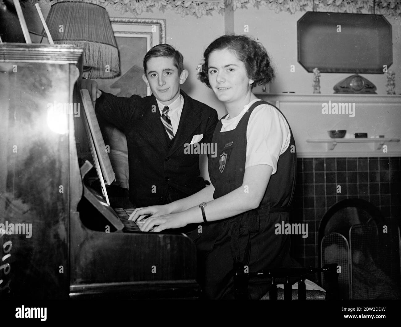 Ronald Bishop, Mitglied der OTC an der Haberdashers Aske's School und Athlet, immatrikulierte mit Auszeichnung im Alter von 14 Jahren und schlug Jack Ralph Blanchfield von Reynolds Park, der die Prüfung im Alter von 15 Jahren bestanden hat. Ronald, Sohn eines Ingenieurs, lebt bei Golders Green. Seine Schwester Dora bestand ihre Matura mit 15 Jahren. Ronald geht nach Cambridge und will Ingenieur werden. Dora wird nächsten Monat nach Oxford gehen. Foto zeigt: Ronald Bishop dreht die Musik für seine Schwester Dora, als sie in ihrem Hause Golders Green Klavier spielt. 19. Oktober 1938 Stockfoto