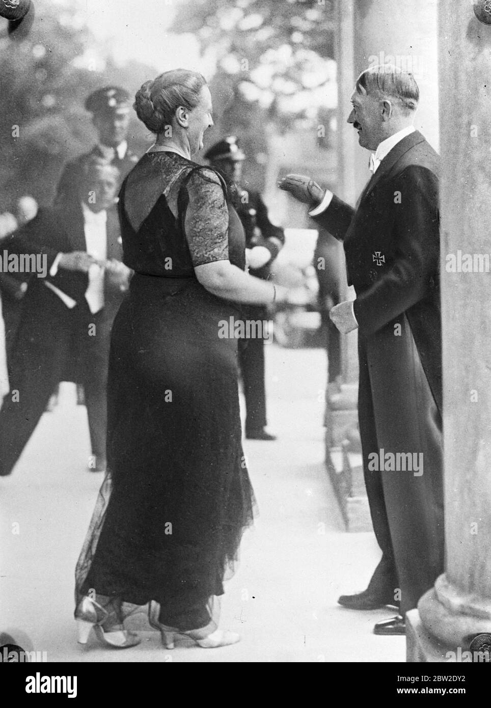 Bundeskanzler Hitler versuchte, Fotografen am Fotografieren zu hindern, als er Frau Winnifred Wagner, mit deren Namen sein eigener immer wieder romantisch verknüpft wurde, zu Beginn der Wagner-Festspiele in Bayreuth in Bayern begrüßte. 26 Juli 1937 Stockfoto