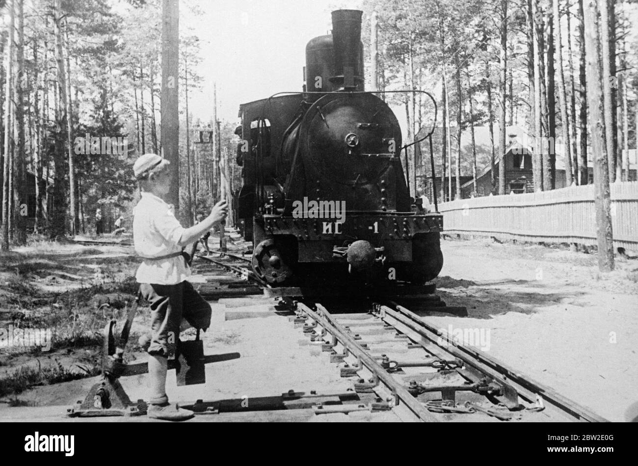 Der diensthabende Knabe, der als eine der Lokomotiven an der Schalter steht, fährt auf eine geplante Fahrt. Die einzige Eisenbahn, die ausschließlich von Kindern genutzt wird, ist in der Sowjetunion nur 25 Meilen von Moskau entfernt im Einsatz. Die Kinder erfüllen alle Aufgaben auf der Bahn, das Miniatursystem dient einem nützlichen Zweck, denn es macht die Jugendlichen mit der Eisenbahntechnik vertraut. 25 Juli 1937 Stockfoto