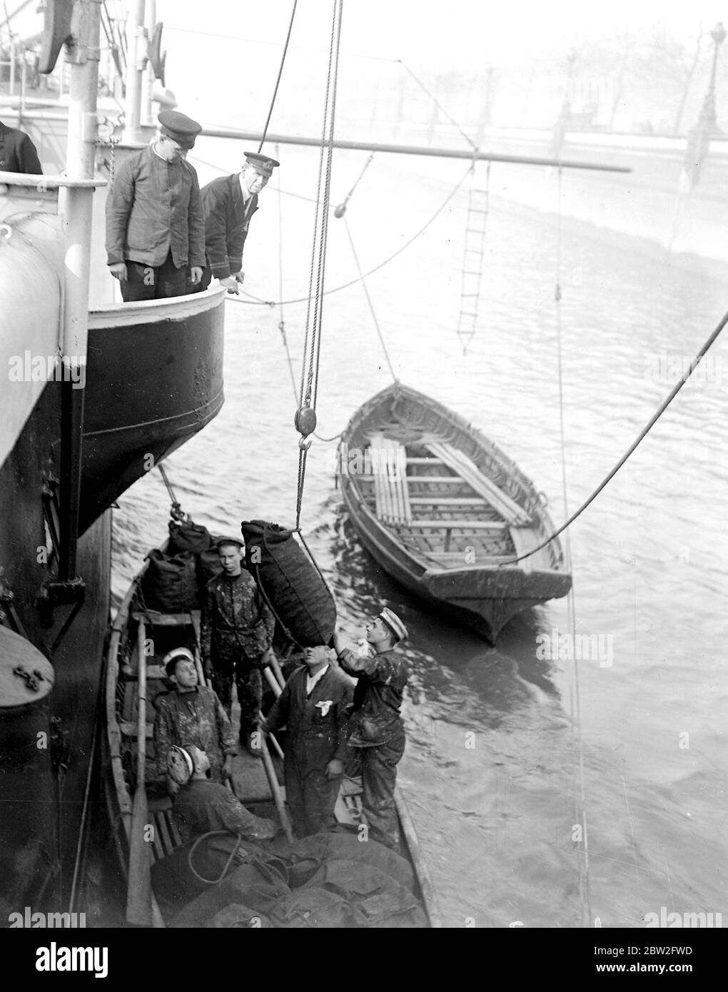 Die Jungs des vor kurzem durch Feuer zerstörten Trainingsschiffes TS Warspite sind nun an Bord des HMS-Präsidenten. Kadetten schleppen Kohle an Bord. März 1918 Stockfoto