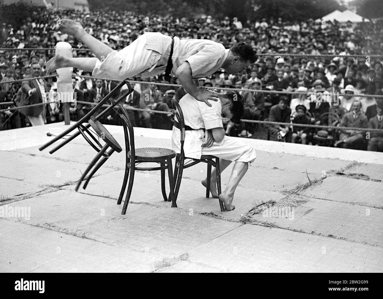 Ju-Jitsu-Demonstration von Herrn George Pape, Gym Instructor am Eton College. Herr Pape macht einen fliegenden Sprung über einen Stuhl, um einen Angriff zu demonstrieren. 14. Juli 1923 eine in Japan entwickelte Kunst der Waffenlosen Selbstverteidigung, die Würfe, Griffe und Schläge verwendet und zusätzliche Kraft aus dem Gewicht und der Stärke des Angreifers ableitet. Stockfoto