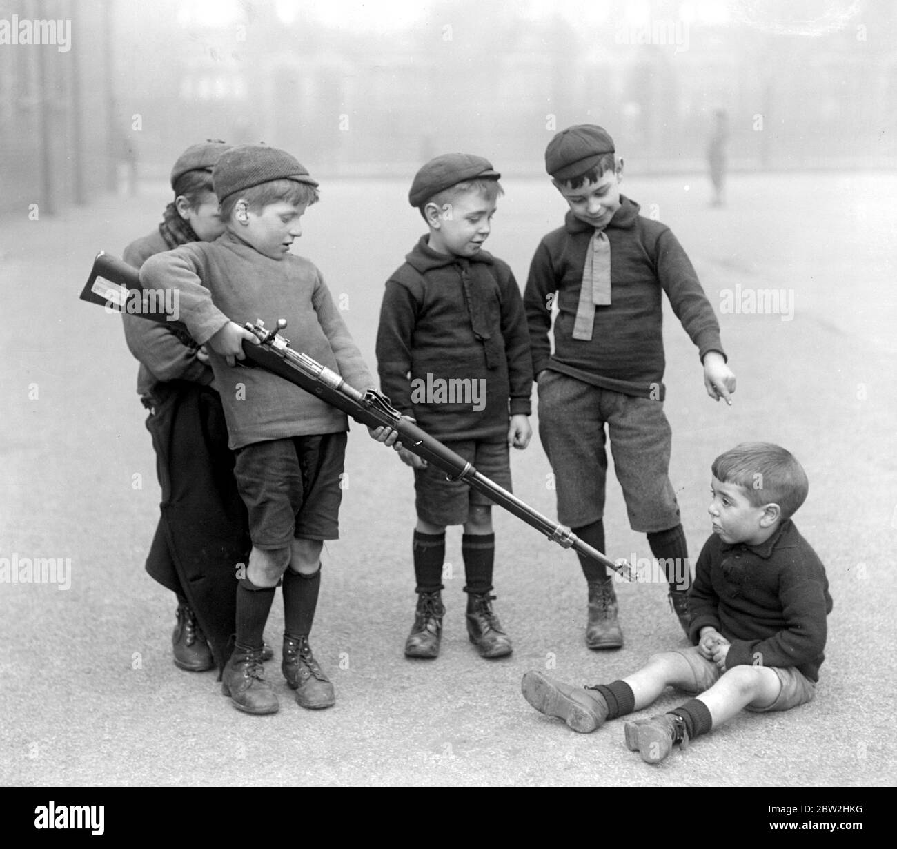 Kleinkinder der Blackhorse Road School, Walthamstow spielen mit einem deutschen Gewehr, das vom Nationalen Sparkomitee vorgestellt wurde. März 1920 Stockfoto