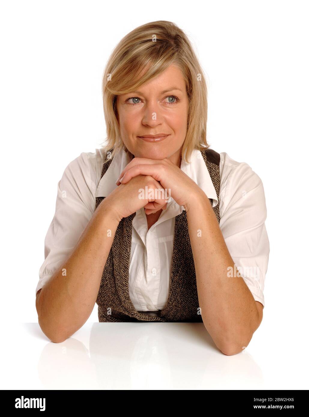 Eine blonde Frau mittleren Alters sitzt an einem Schreibtisch Stockfoto