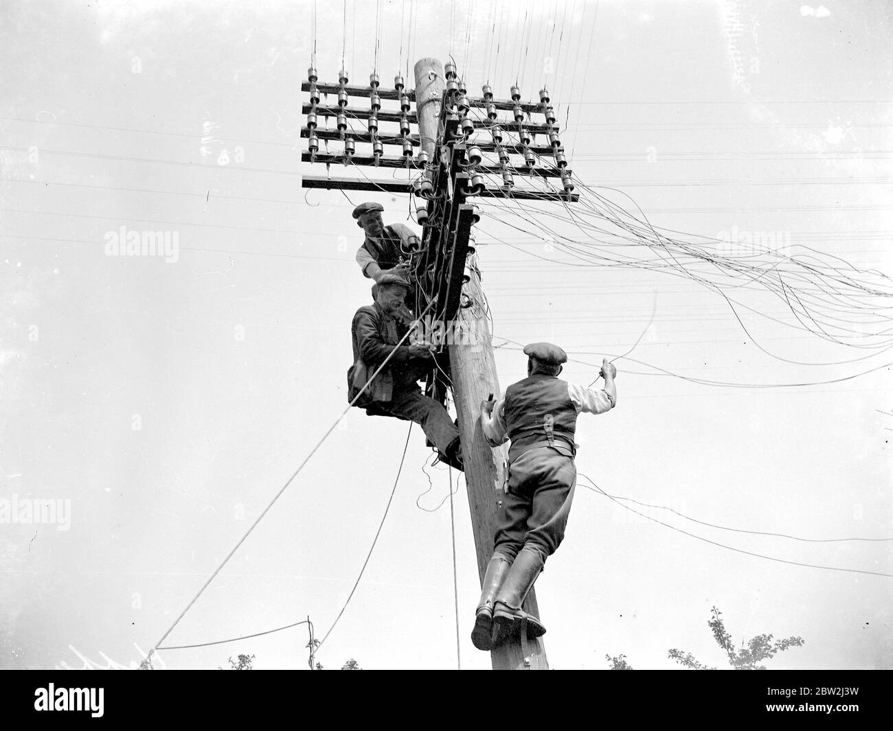 Telegraph Wire Männer arbeiten hoch oben auf dem Telegrafenpfosten. 1934 Stockfoto