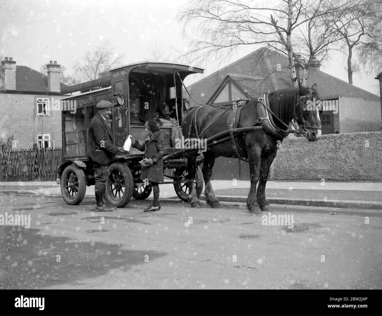 Mädchen, das Milch von einem Milchmann neben seinem Milchwagen der Dartford Cooperative Society kauft, einen Wagen, der von einem Shire-Pferd gezogen wird. 1934 Stockfoto