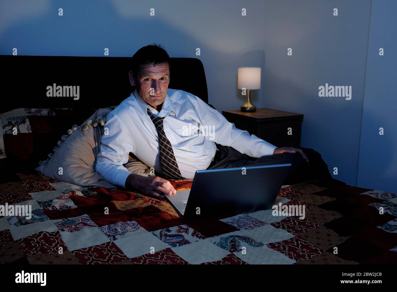 Ein Geschäftsmann, der spät am Laptop im Hotelzimmer arbeitet Stockfoto