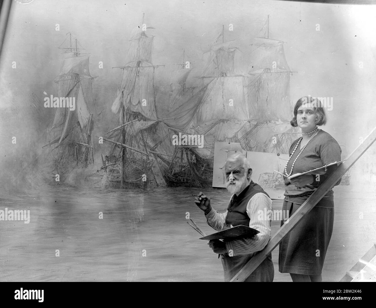 Herr W. L. Wyllie, R.A, unterstützt von seiner Tochter, bei der Arbeit an seinem Gemälde der Schlacht von Trafalgar, die im New Victory Museum in Portsmouth aufgehängt werden. Die Leinwand ist 36ft x 12ft. Die Aufgabe des Auflegens auf die Farbe war, die Farbe auf sehr dick zu klumpen und dann mit den Händen glatt. Die Arbeiten haben bereits über ein Jahr gedauert und sind nun fast abgeschlossen. 16. Mai 1930 Er starb am 6. April 1931 Stockfoto