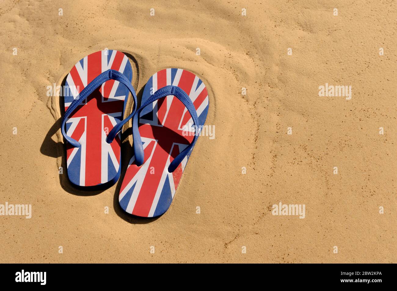 Ein Paar Union Jack Flip-Flops auf goldgelbem Sand Stockfoto