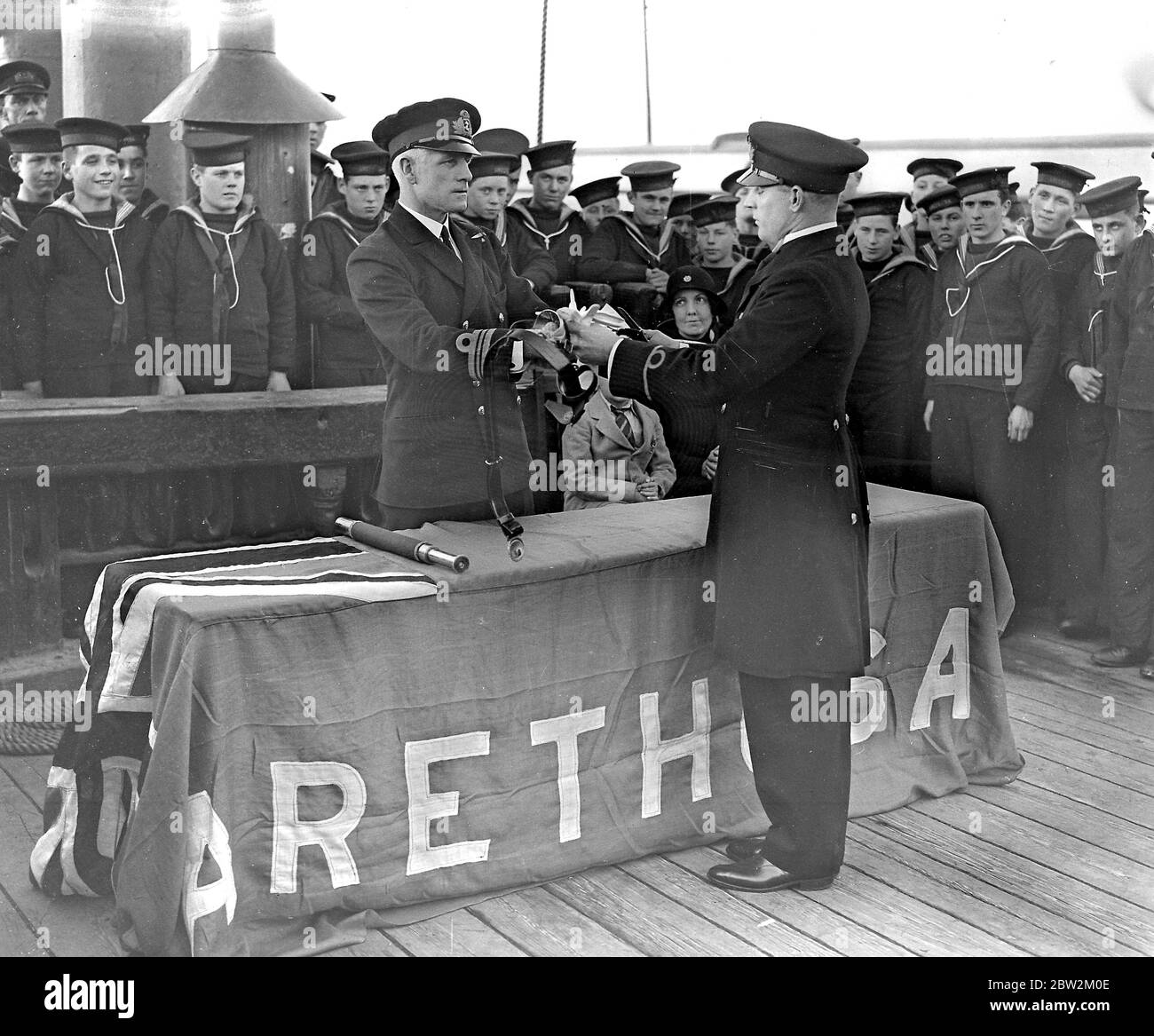 An Bord des Arethusa-Trainingsschiffes. Commander C.W. Bower (befehligender Arethusa) übergibt John Stonor, einem alten Arethusa-Jungen, ein Schwert, nachdem er den Rang eines Warrant Officers in der Royal Navy erreicht hat. Stockfoto
