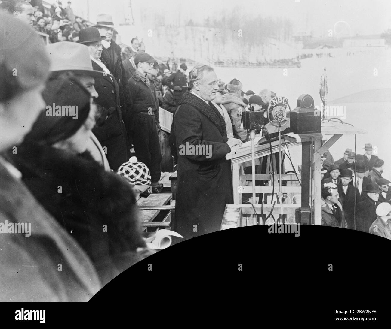 Die Olympischen Winterspiele wurden offiziell am Lake Placid eröffnet. Gouverneur Franklin D Roosevelt von New York führte die Eröffnungszeremonie der Olympischen Winterspiele 1932 am Lake Placid, New York in Anwesenheit von 350 Athleten aus 17 Nationen. Gouverneur Franklin D Roosevelt wendet sich an die Athleten aus verschiedenen Nationen vor der Tribüne bei der Eröffnungsfeier . 14 Februar 1932 Stockfoto