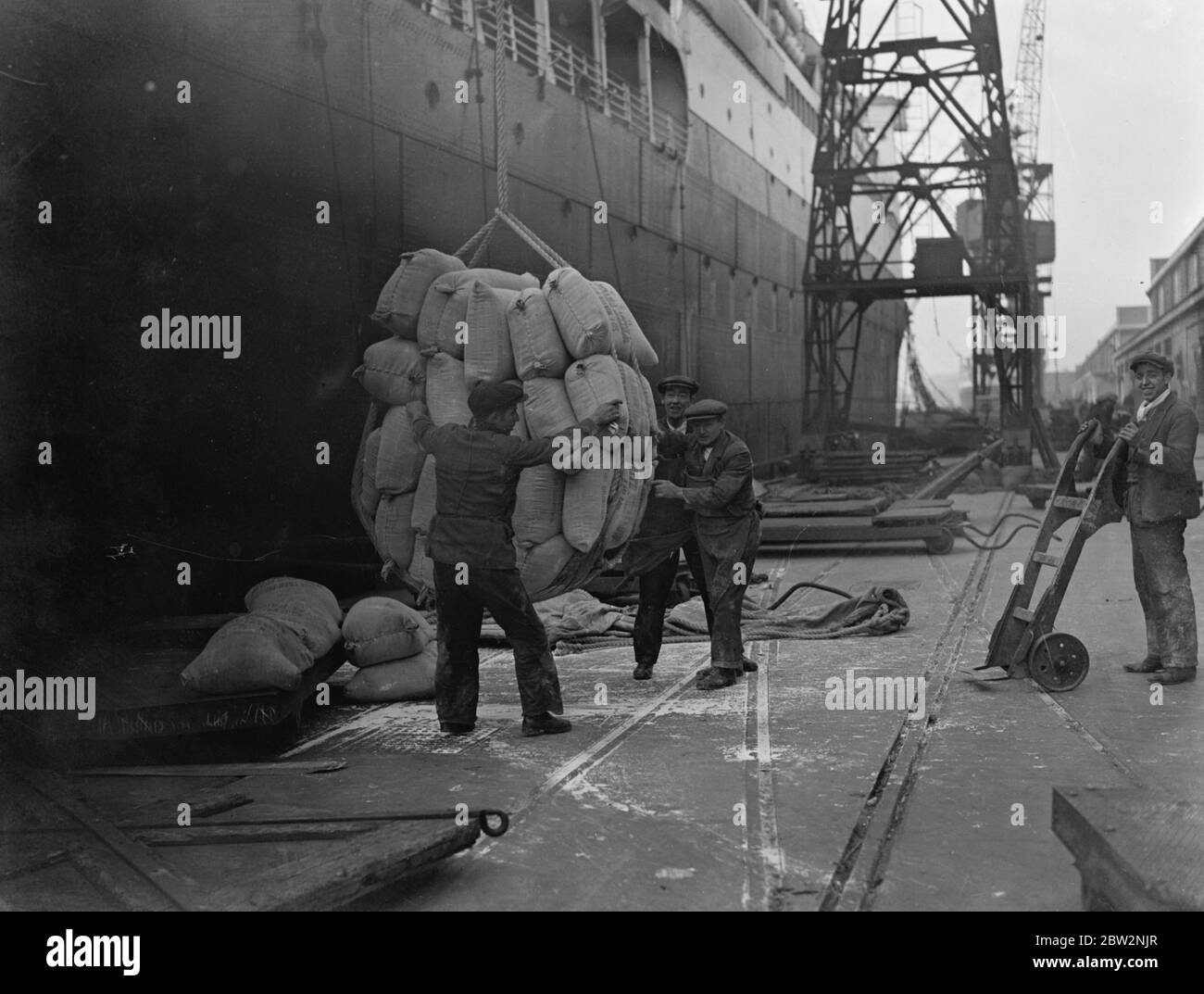 Sonntag Entladen, um überfüllte Docks zu entlasten, wie Schiffe nach London eilen, um Tarife zu vermeiden. Den ganzen Tag Sonntag der König George V Docks präsentiert eine Szene von beispielloser Aktivität, wie Schiffe wurden entladen und Waren an Land eilte, um die neuen Tarife, die wirksam werden Dienstag zu entkommen. Das Mehl vom SS-Präsidenten Harding zu entladen, ein amerikanisches Linienschiff, das zum ersten Mal an der Themse andockte. 28. Februar 1932 30er, 30er, 30er, 30er, 30er, 30er Jahre Stockfoto