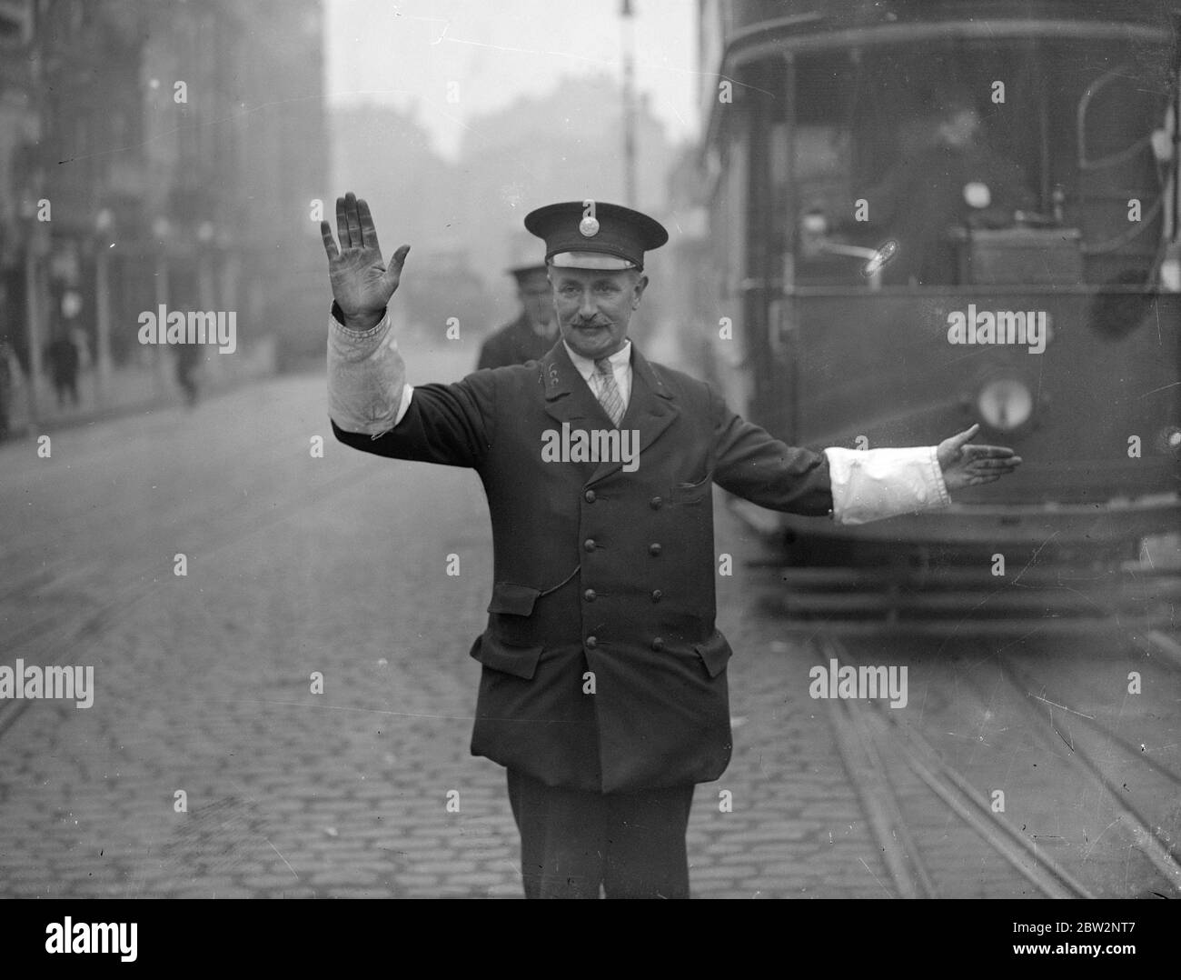 Weiße bewaffnete Straßenbahn Inspektoren als Polizeiassistenten in London, neue Straße Sicherheit bewegen. Weiße Armbinde wurden an Straßenbahnen Inspektoren und Regulatoren des Londoner County Council zur Verwendung bei der Kontrolle des Verkehrs in Verbindung mit der Polizei ausgestellt. Dies ist die neueste Anstrengung in Verbindung mit der Sicherheit auf der Straße. Einer der neuen weißen gepanzerten Straßenbahnregulatoren im Dienst Unterstützung eines Polizisten in St Georges Circus, London. 25. September 1931 Stockfoto