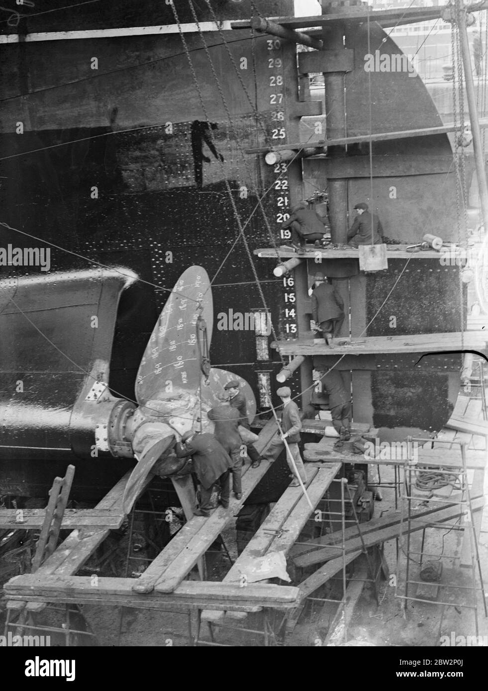 Überholung für einen Ozeanriesen. Untersuchung eines der riesigen Propeller der Cunard Liner Austonia während ihrer Überholung im Royal Albert Dry Dock, Silvertown, London. 10. April 1934 Stockfoto