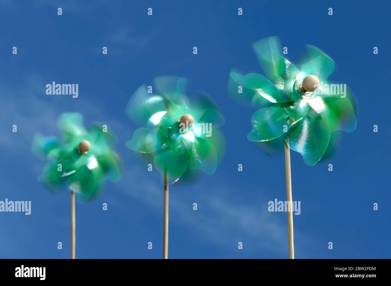 Drei grüne Nadelrad-Windmühlen, die im Wind wehen Stockfoto