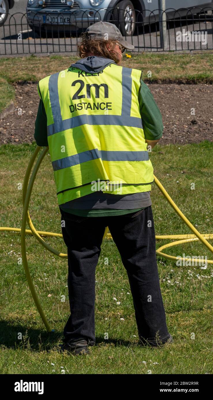 Southsea, Portsmouth, England, Großbritannien. Mai 2020. Ein kommunaler Schlüsselarbeiter, der eine reflektierende Jacke mit den Worten „Keep 2m Distance“ trägt. Während Covid-19 Stockfoto