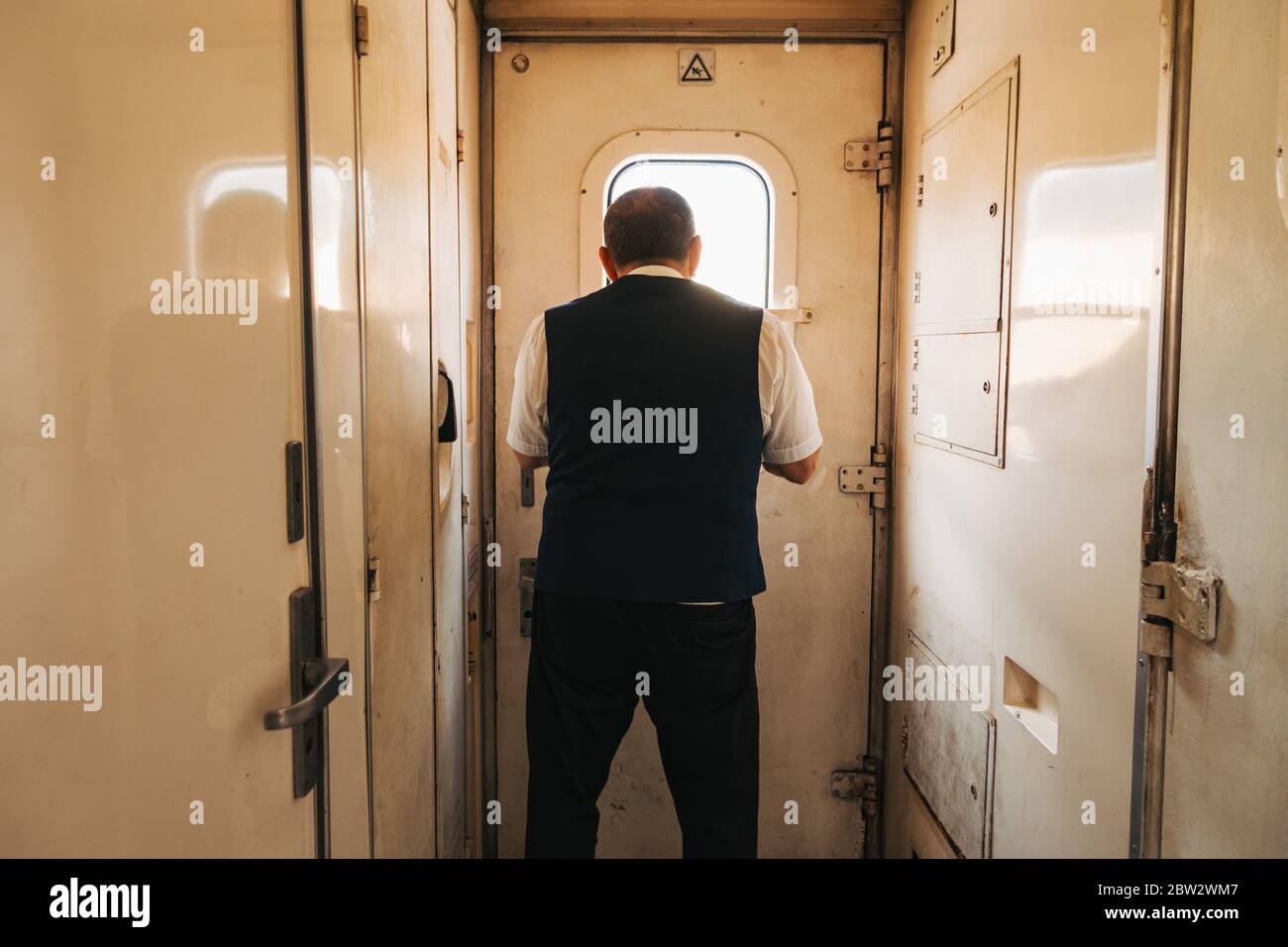 Ein Zugbegleiter bereitet sich darauf vor, die Tür zu öffnen, während der Zug sich einem Bahnhof in Gori, Georgien, nähert Stockfoto