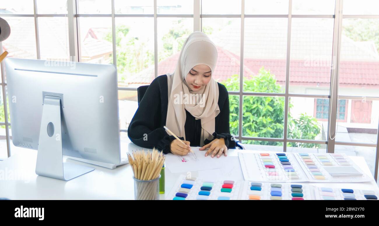 Kleine Unternehmen von Moslem-Frauen Modedesignerin, Die Mit Smartphone und Tablet Mit Kleider im Bekleidungsgeschäft arbeitet und verwendet Stockfoto