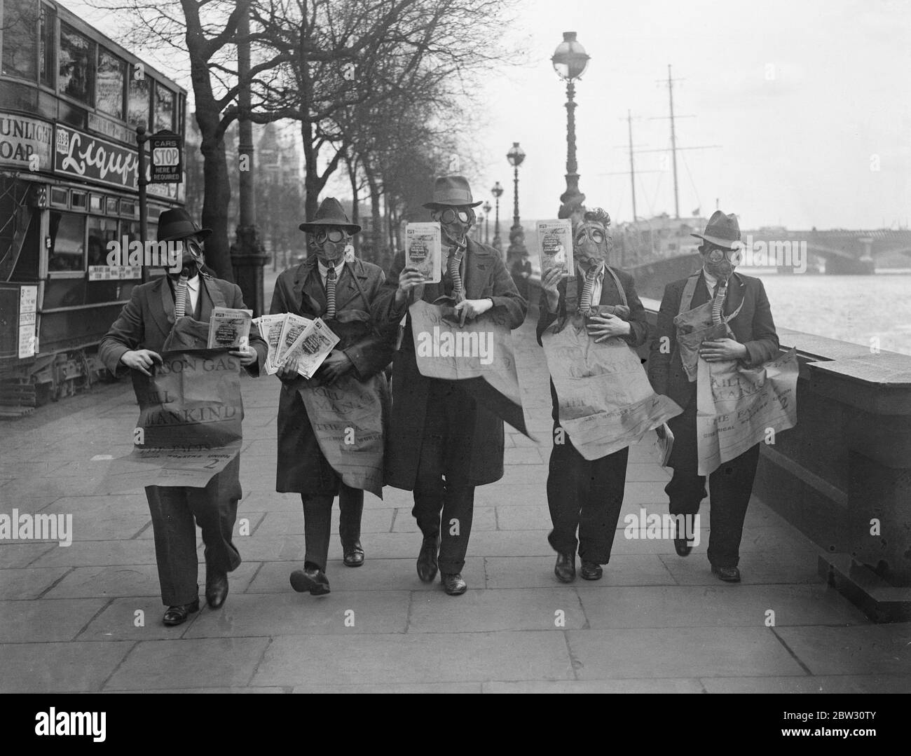 Gasmaskierte Demonstranten veranstalten die Maiparade in London. Demonstranten tragen Gasmasken und tragen Plakate drängen auf die Abschaffung der Gas-und chemischen Krieg, leitete die Maifest Parade durch London, die von der Uferstraße begann. Demonstranten weraing Gasmasken marschieren entlang der Embankment, London bei der Demonstration am 1. Mai. 29. April 1932 Stockfoto