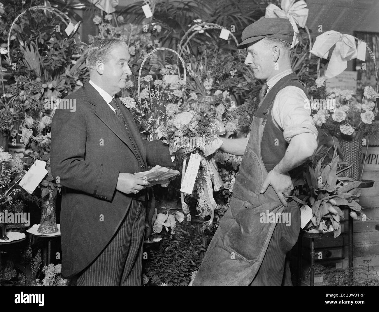 Fünfzig Jahre in Covent Garden . Herr William Benjamin Shearn , der heute sechzig Jahre alt ist , und seit fünfzig Jahren Obst und Gemüse in Covent Garden verkauft , erhielt mehr als 100 Blumensträuße von Blumen und Gemüse von Freunden und Trägern, um die Veranstaltung zu markieren . Herr William Benjamin Shearn erhält einen Blumenstrauß Gemüse von einem Portier in Covent Garden, London. 23. Januar 1932 Stockfoto