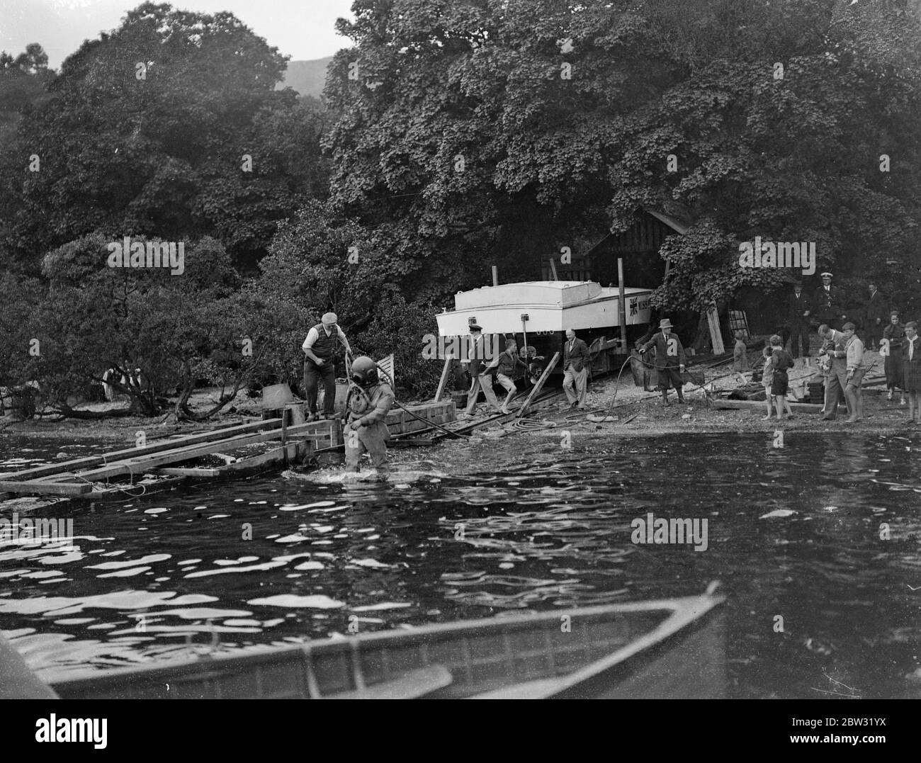 Geschwindigkeitsrekordtests wieder verschoben, wenn Miss England III Fouls Slipway . Kaye Don einen weiteren Schlaganfall von Unglück in seinem Versuch, den Weltrekord für die Wassergeschwindigkeit für Großbritannien in Miss England III gewinnen, Lord Wakefield ' s £ 40, 000 Speed boat, am Loch Lomond, Schottland, Als die Slipanlage, die zum Wasser führt, zusammenbrach und ein Loch im Rumpf des Bootes zerrissen wurde. Admiralty Taucher arbeiteten die ganze Nacht, um die Slipway zu ersetzen und machen eine Unterwasser-Untersuchung der Arbeit. Arbeiter bringen eine neue Schiene zum Ufer, um die gebrochene zu ersetzen, während ein Taucher bereit steht, um zu kommen Stockfoto