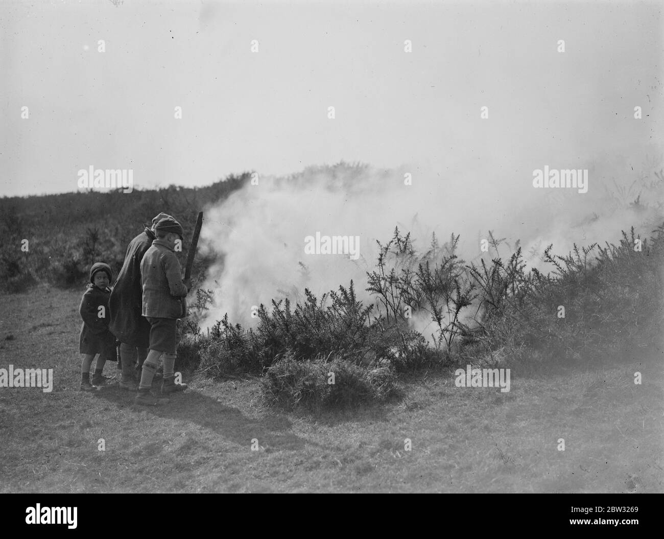Große gemeinsame Feuer in der Nähe von Eastbourne . Ein großes gemeinsames Feuer lag Abfälle Hektar Heide in der Nähe von Birling Gap , die berühmte Sussex Schönheit Ort in der Nähe von Eastbourne . Kinder beobachten die brennende gemeinsame während des Feuers . 26 März 1932 Stockfoto