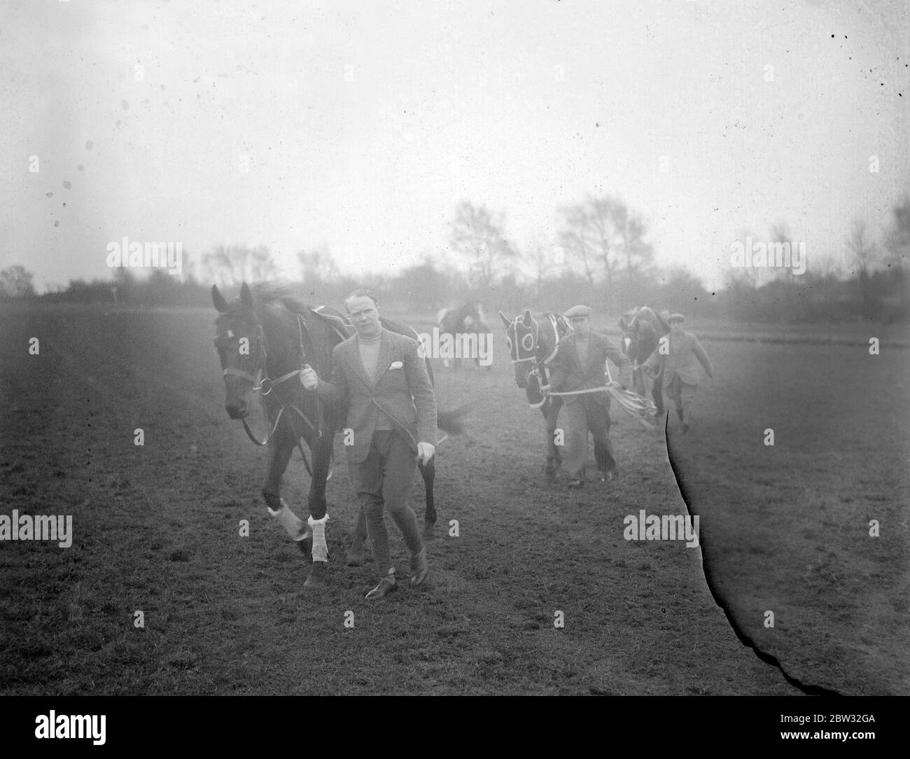 Neuer Epsom Trainer beginnt die Arbeit für die großen Rennen. Eine Lizenz zum Zug wurde gerade von der Jockey Club Herrn Arthur S Boxall , ein bekannter North London Estate Agent , der in Epsom gelebt hat und besaß Pferde für eine Reihe von Jahren gewährt. Herr Boxall führt seine Trainingsarbeit in den sehr frühen Morgenstunden und hat einige wahrscheinlich Kandidaten in Vorbereitung auf die großen Rennen in diesem Sommer , einschließlich Sprint , der in der Stadt und im Vorburban engagiert . Herr Arthur Boxall auf Sprint, führt seine Zeichenfolge in der frühen Morgenstunden Training auf Epsom Downs, Surrey. April 1932 Stockfoto