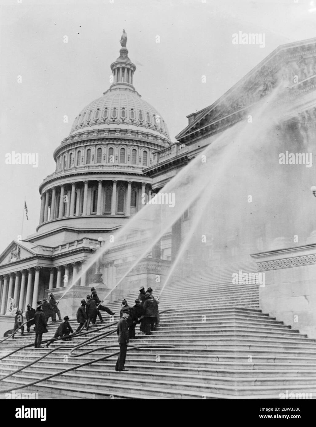 Das Capitol bekommt sein jährliches Bad. Das berühmte Capitol Gebäude in Washington, DC erhielt sein jährliches Bad von den Feuerwehrleuten der Stadt. Feuerwehrleute, die mächtige Wasserströme aus ihren Schläuchen auf das Kapitolgebäude lenken, während sie ihm sein jährliches Bad geben. November 1932 Stockfoto