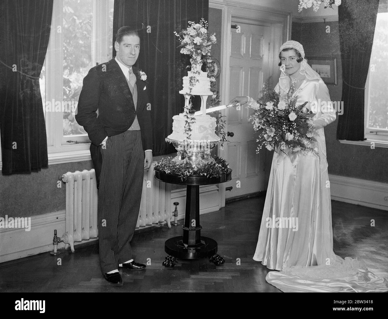 Tochter von Direktor von Phosferine vermählt Scotsman. Die Hochzeit von Miss Everall Tallock, Tochter eines Direktors von Phosferine zu Herrn W. F. Wilson von Edinburgh fand in St Mary 's Catholic Church, Chislehurst. Die Braut schneidet den Kuchen mit dem Bräutigam, an der Rezeption. Februar 1932 Stockfoto