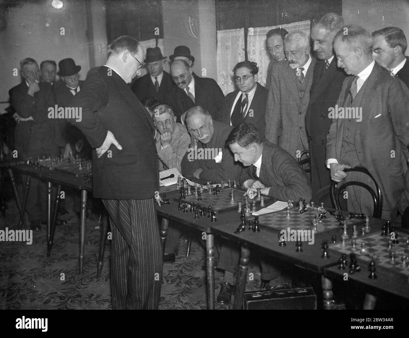 DR Alekhine Schachweltmeister spielt Konkurrenten gleichzeitig in London. Dr. Alekhine, der Schachweltmeister, spielte fünfundzwanzig Konkurrenten auf einmal bei einem Turnier im Empire Chess Club, Bayswater, London. Dr. Alekhine ( stehend ) während seines gleichzeitigen Spiels gegen fünfundzwanzig Spieler im Empire Chess Club . 29. Januar 1932 Stockfoto