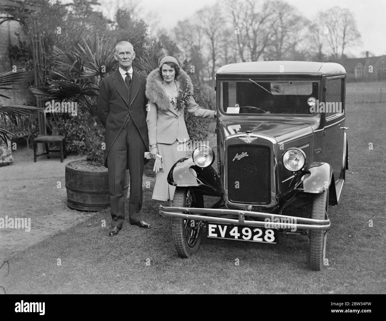 Siebzig sieben Jahre alt Essex Dorf Vikar vermählt zweiunddreißig Jahre alte Krankenschwester. Die Rev RRVC Graves OBE, Vikar von Tolleshunt D'Arcy, war mit Miss Mildred Nicolas verheiratet, eine zweiunddreißig Jahre alte Krankenschwester, in seiner Pfarrkirche in Tolleshunt, Essex. Der 77 Jahre alte Pfarrer. Die Braut und der Bräutigam mit dem Auto, das der Braut vom Bräutigam präsentiert wird. April 1932 Stockfoto