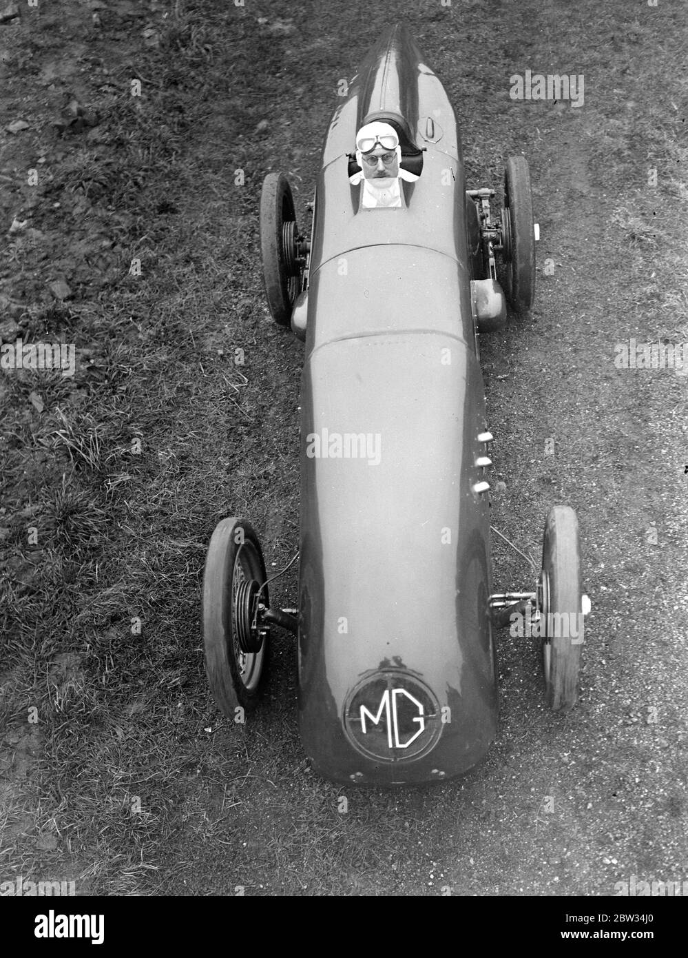 G E T Eyston bereitet sich auf Angriff auf Weltrekord für Baby-Autos in Pendine Sands . Herr G E T Eyston, der Rennfahrer, macht die letzten Vorbereitungen für seinen Versuch, einen neuen Weltrekord für Baby-Autos mit seinem MG The Magic Midget, die auf Pendine Sands, Carmarthenshire, Wales stattfinden wird. Er wird einen speziell angefertigten Asbestanzug tragen. Ein ungewöhnliches Bild von Herrn Eyston im Cockpit seines Autos, das gemacht wird, um ihn zu passen. Februar 1932 Stockfoto
