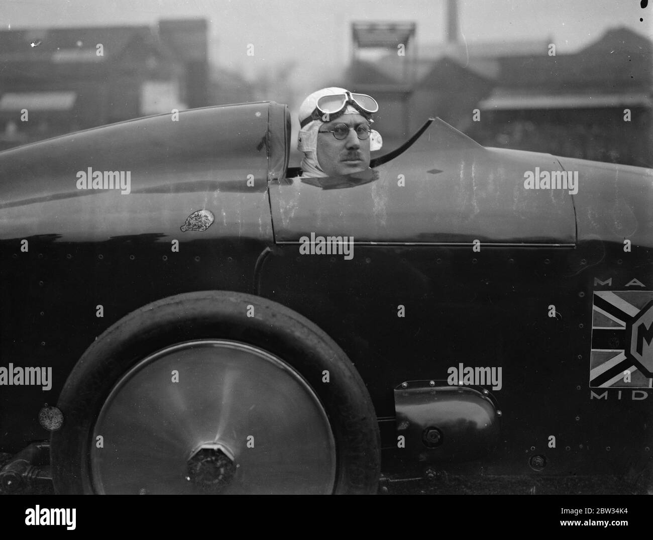 G E T Eyston bereitet sich auf Angriff auf Weltrekord für Baby-Autos in Pendine Sands . Herr G E T Eyston, der Rennfahrer, macht die letzten Vorbereitungen für seinen Versuch, einen neuen Weltrekord für Baby-Autos mit seinem MG The Magic Midget, die auf Pendine Sands, Carmarthenshire, Wales stattfinden wird. Er wird einen speziell angefertigten Asbestanzug tragen. Ein ungewöhnliches Bild von Herrn Eyston im Cockpit seines Autos, das gemacht wird, um ihn zu passen. Februar 1932 Stockfoto