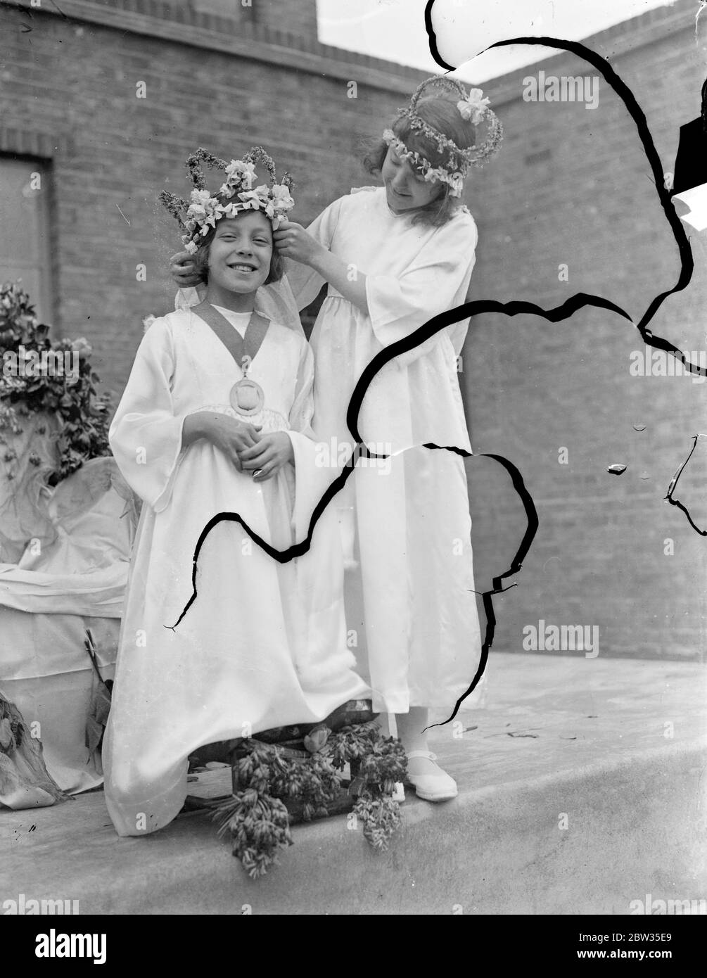 Erster Mai Königin des Jahres gekrönt in Dagenham . Die Dagenham Mai Königin, die erste des Jahres, wurde in der Osborne Hall gekrönt, Dagenham. Die neue Königin, Olive Smith, im Alter von 10, wurde von der alten Königin gekrönt, Patricia Cane im Alter von 12. Die alte Königin Patricia Cane krönt die neue Königin von Dagenham Olive Smith. 29. April 1933 Stockfoto