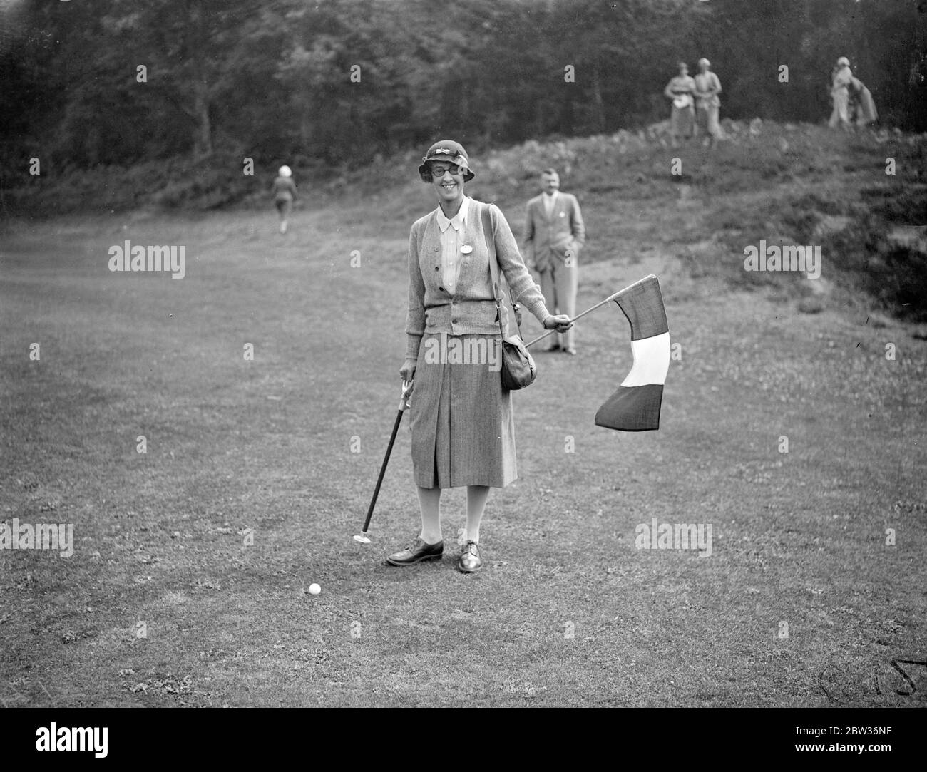 Golferinnen aus Großbritannien und Frankreich treffen sich im internationalen Spiel. Das internationale Spiel zwischen Golferinnen aus Großbritannien und Frankreich fand auf dem St. George ' s Hill Course in Weybridge, Surrey statt. Foto zeigt ; Lady Alness hält die französische Flagge über den Ball, als das Spiel eröffnet . 29 Juni 1933 Stockfoto