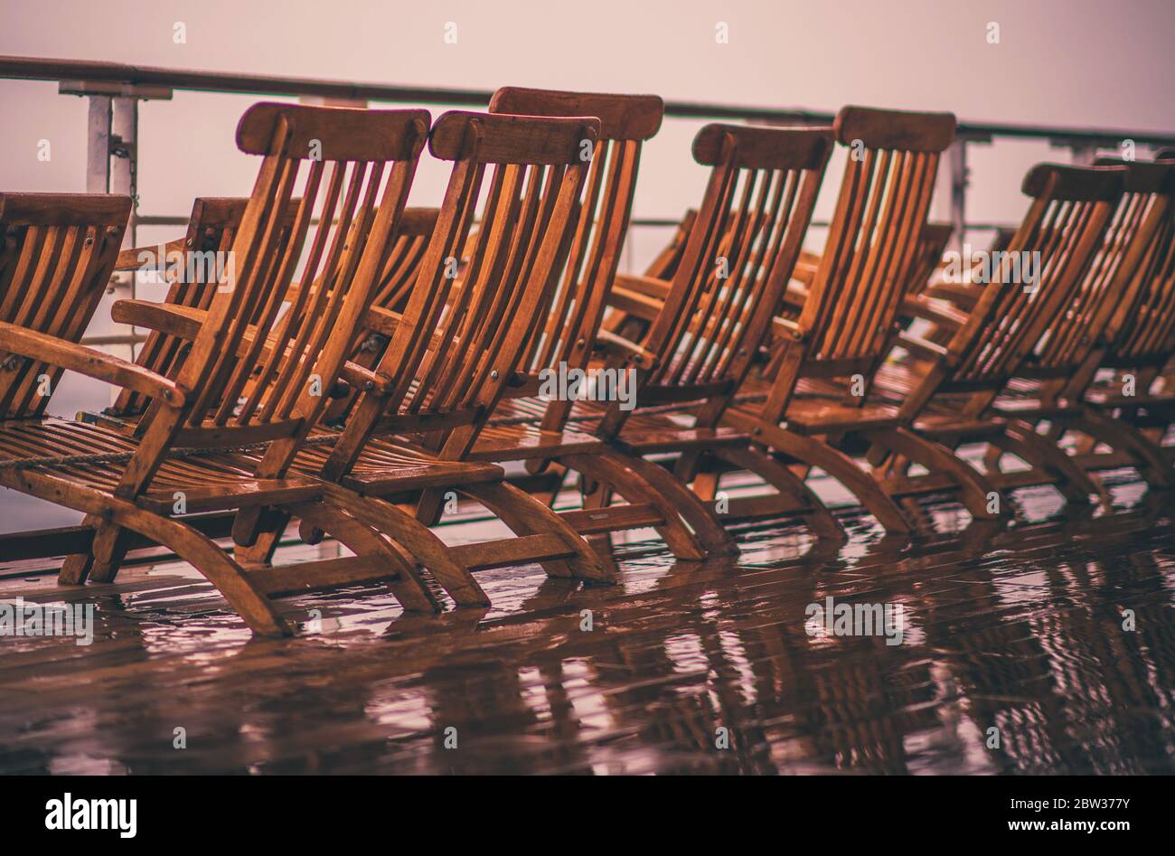 Probleme In Der Reisebranche. Leere und nasse Holzliegestühle für Kreuzfahrtschiffe. Stockfoto