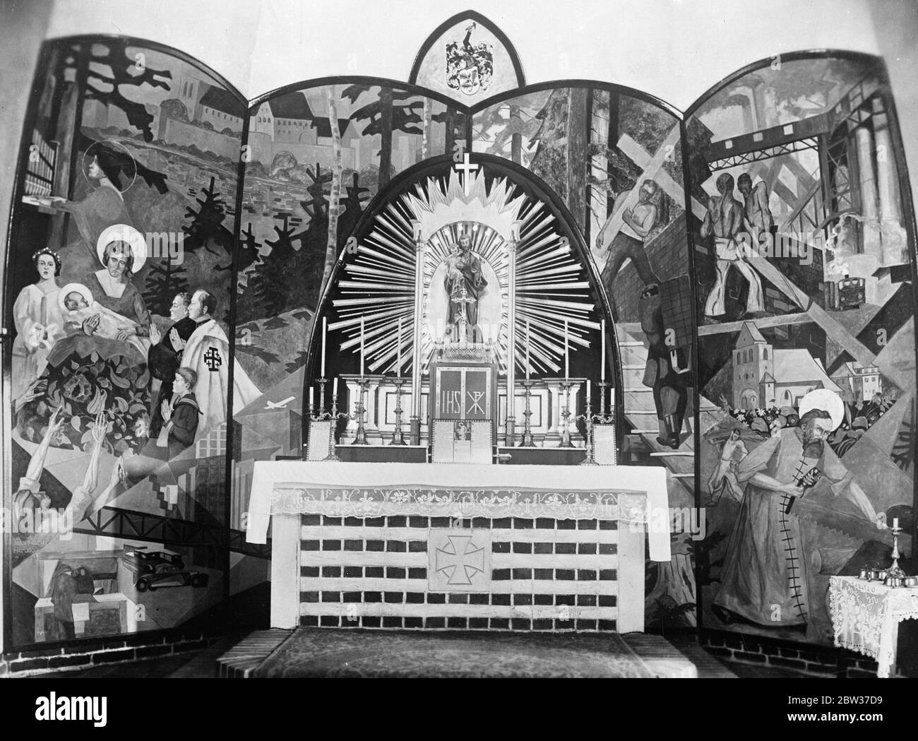 Rennwagen, Fabriken, moderne Kleidung für bemerkenswerte Altar für neue katholische Kirche in Deutschland. Einer der bemerkenswertesten Altäre in der Welt, dass in der neuen katholischen Kirche gerade in Strausberg, Deutschland abgeschlossen. Das Altarbild, das Werk des großen deutschen Künstlers Professor Max Malitz, ist ein Farbaufstand, der biblische Szenen in moderner Tracht darstellt. Arbeiter, in einem Hintergrund zeigt eine moderne Fabrik, werden gesehen, die das Kreuz tragen, moderne Rennwagen sind in einer Szene integriert, während die weisen Männer verehren die christus Kind als Ekklesiastiker in modernen Gewändern gesehen werden. Fotoschau Stockfoto