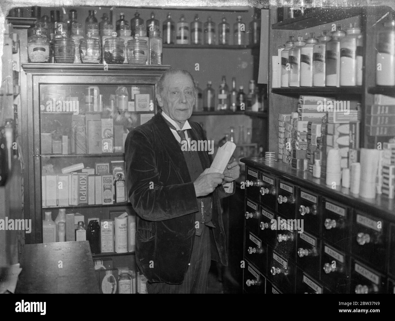 Herr S J Powell , der seit vielen Jahren beruflich mit Madame Patti verbunden war, und der prominente Rollen in Theaterstücken und Filmen gespielt hat, ist nun Mitinhaber eines kleinen Chemikers Shop im Tempel, London. In den letzten 56 Jahren hat Herr Powell mit einigen der größten Persönlichkeiten in der Musik und der Bühne verbunden. Er lernte Klavier zu spielen, als er vier Jahre alt war. Herr SJ Powell in seinem Haus im Tempel . 12. Januar 1934 Stockfoto