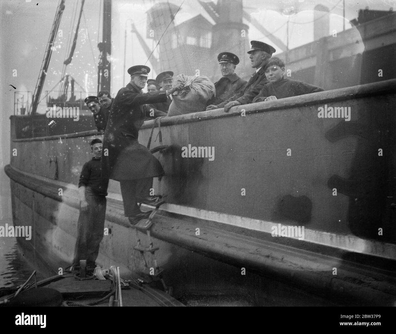 Verteilung von weihnachtsgeschenken an Thames Watermen . Die jährliche Verteilung von Weihnachtsgeschenken an Thames Watermen durch die Missionen an Seemann fand auf dem Fluss statt, als Reverend F J Cutts Geschenke verteilte. Foto zeigt ; Reverend F H Cutts verteilen Geschenke an eine Sunderland Collier auf der Themse in der Nähe von Woolwich . 21 Dezember 1933 Stockfoto